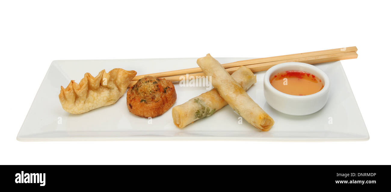 Chinese Dim Sum snacks with a sweet chilli dip and chopsticks on a rectangular plate isolated against white Stock Photo