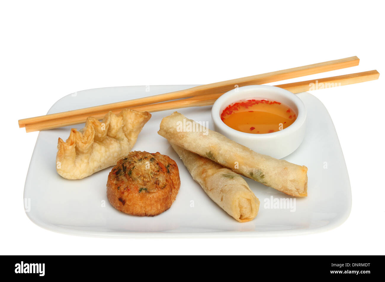 Chinese Dim Sum on a plate with chopsticks and a sweet chilli dipping sauce isolated against white Stock Photo