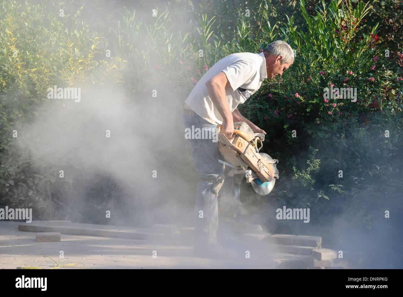A builder uses an angle grinder to cut bricks while laying a patio Stock  Photo - Alamy