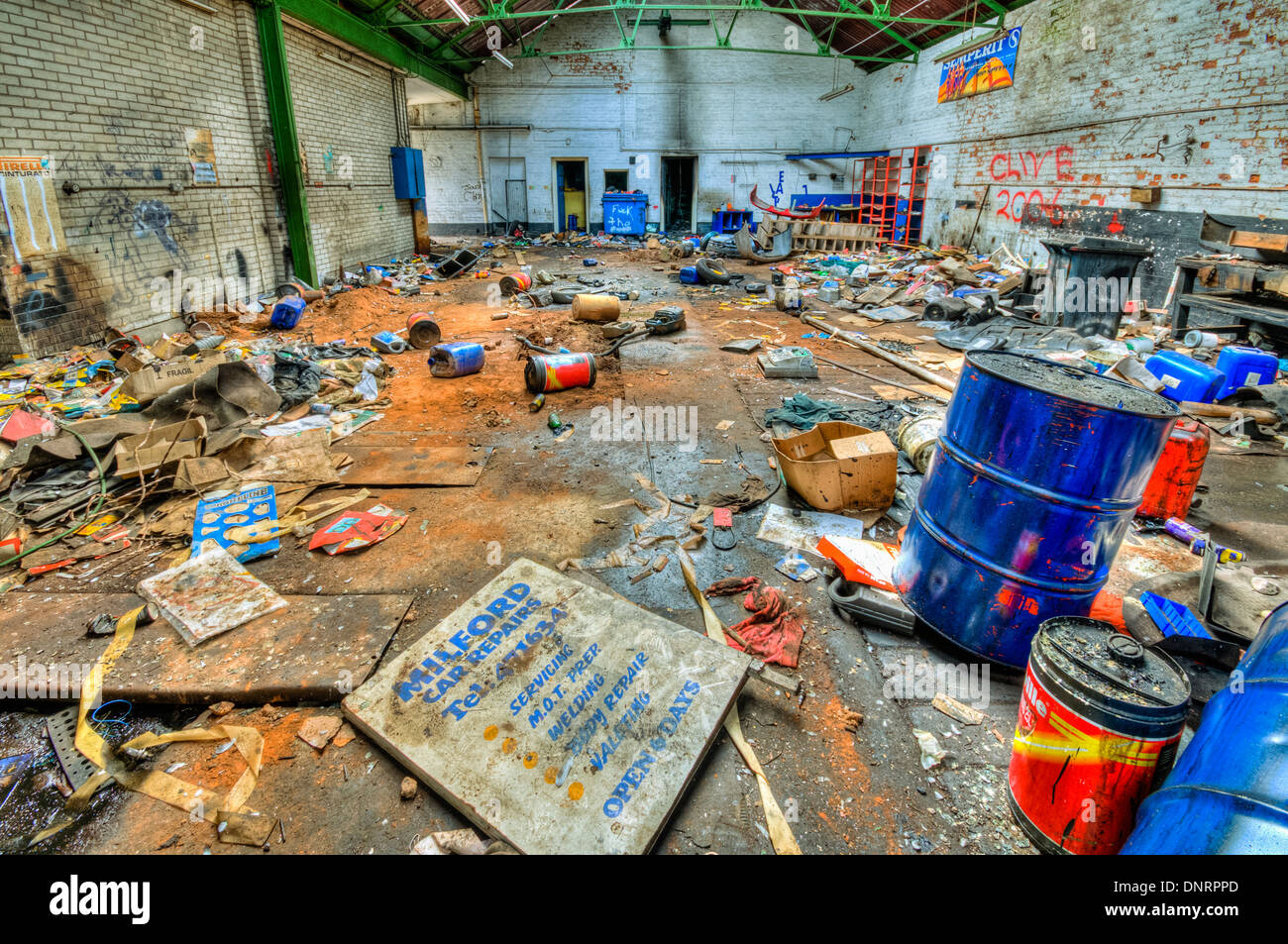 Oil drums and canisters thrown about an abandoned garage Stock Photo
