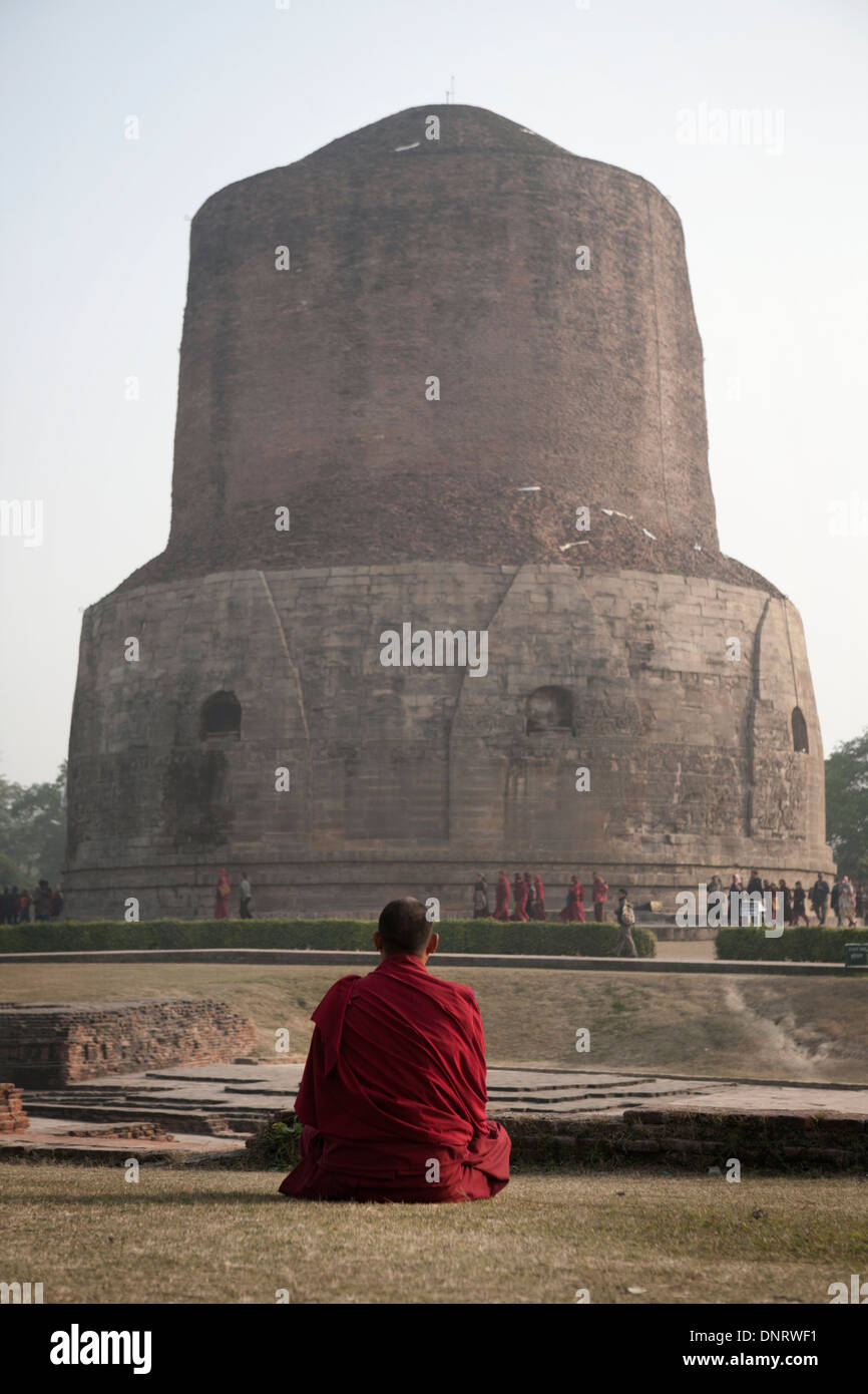 Tibetan monk meditates at the Dhamek Stupa in Sarnath, Uttar Pradesh, marking the spot where the Buddha held his first sermon. Stock Photo