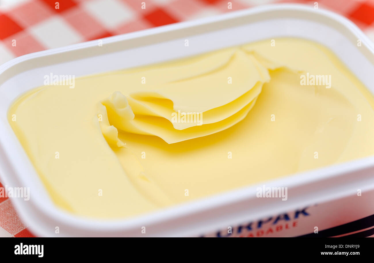 An open tub of Lurpak butter on a red gingham background Stock Photo