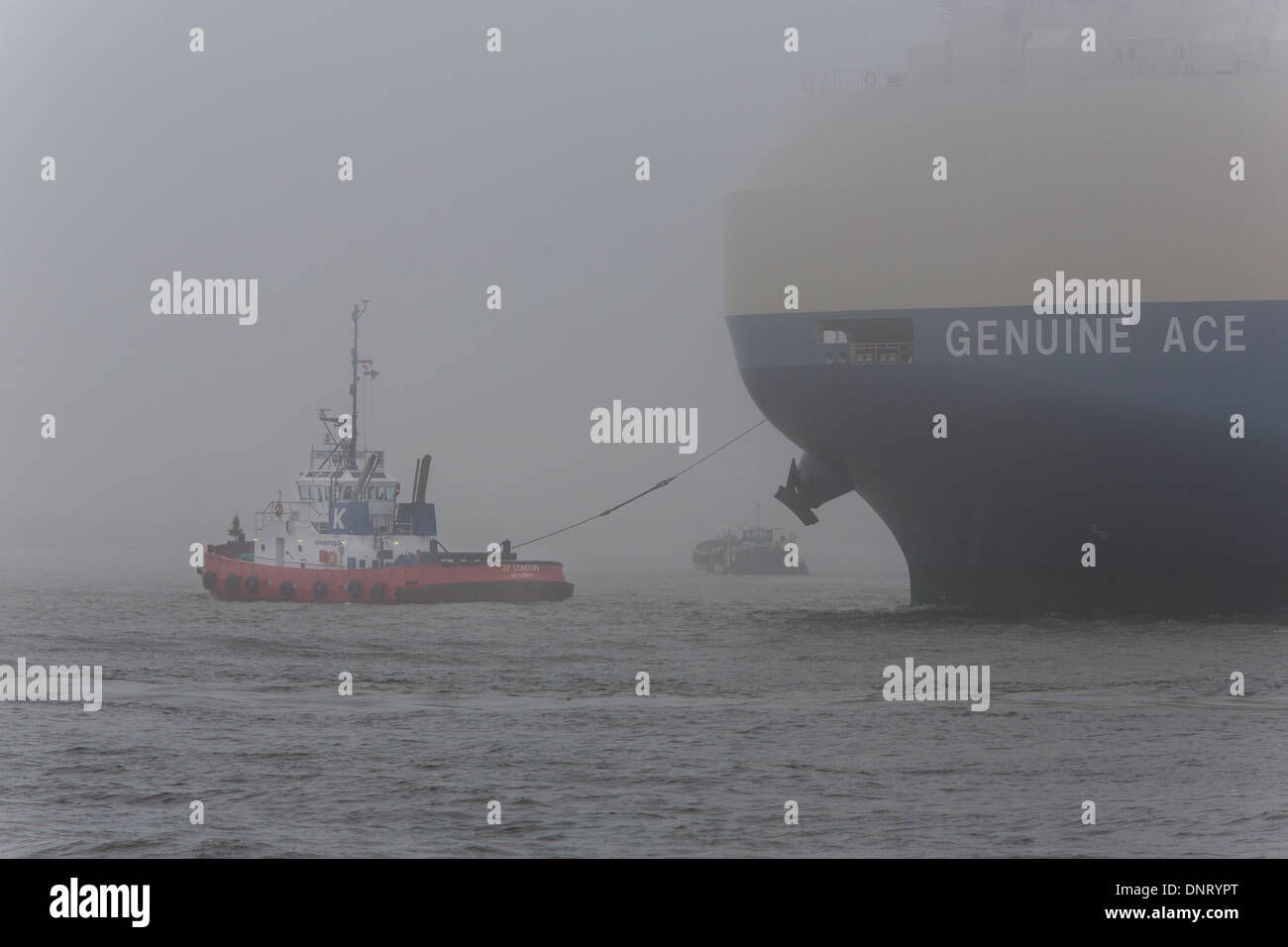 A tugboat with a freighter at Hamburg harbour with fog, Germany Stock Photo