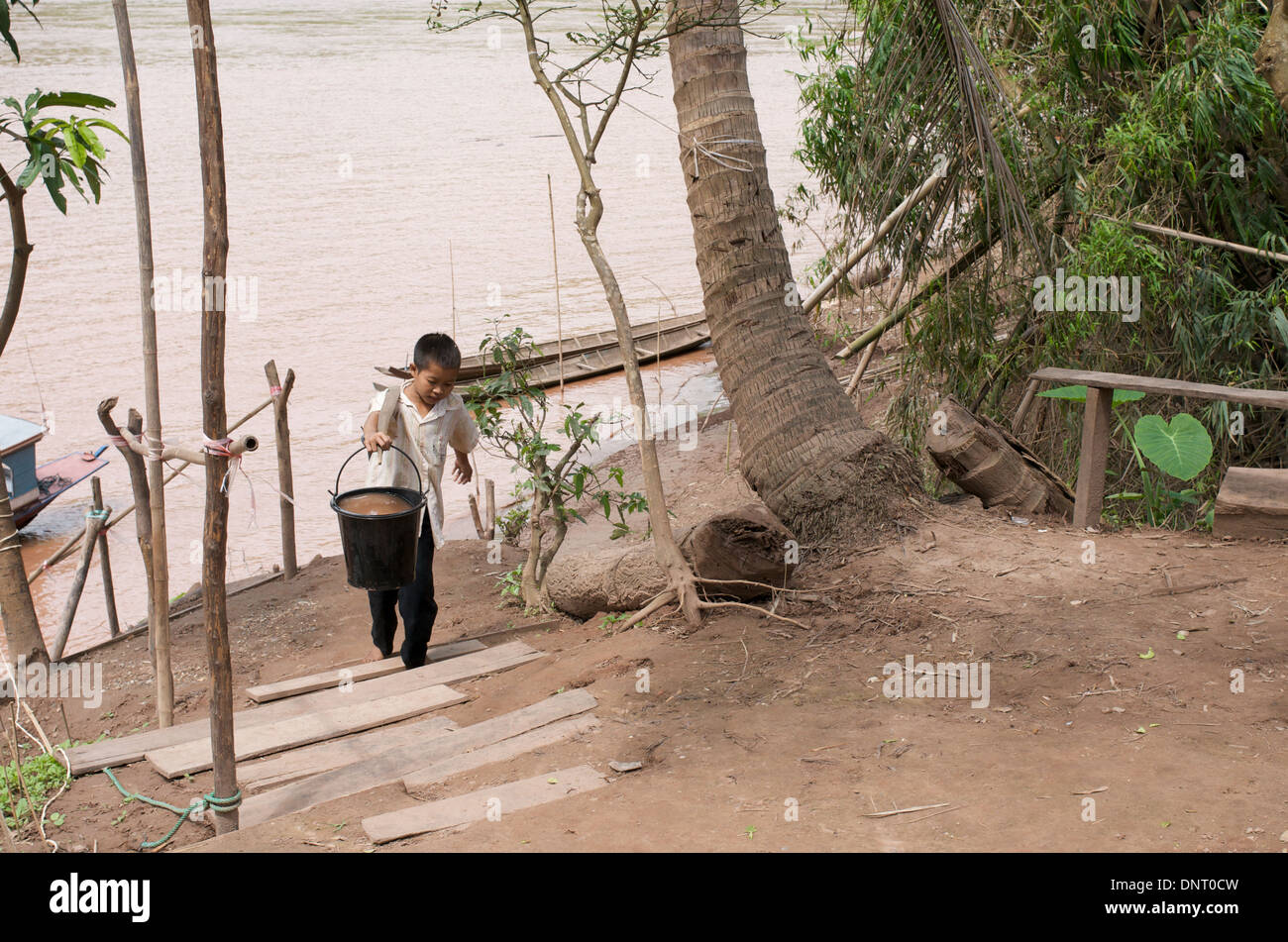 Young boy carrying water by the Mekong River in Laos Stock Photo