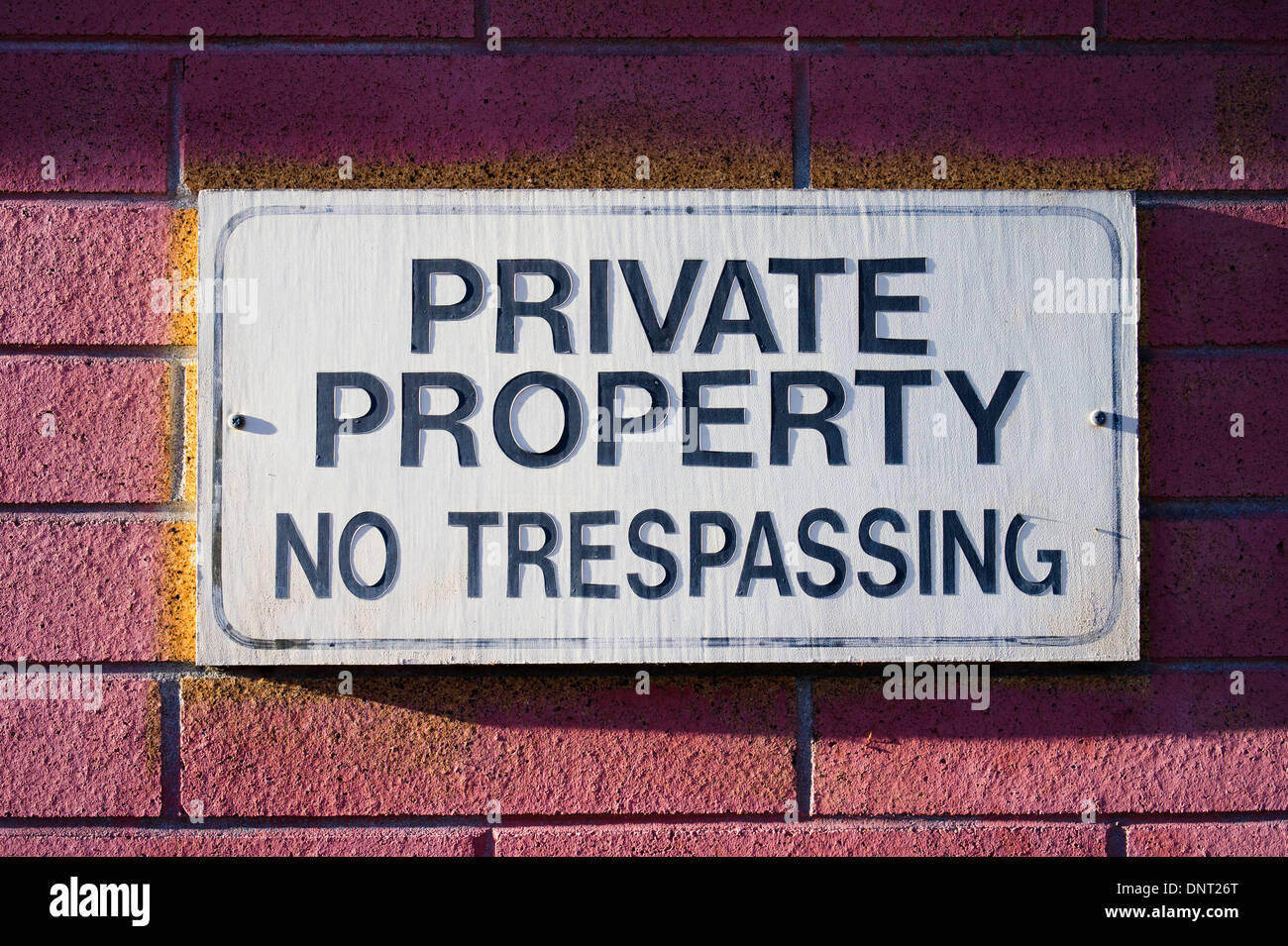 Faded sign on brick wall 'Private Property No Tresspassing' Stock Photo