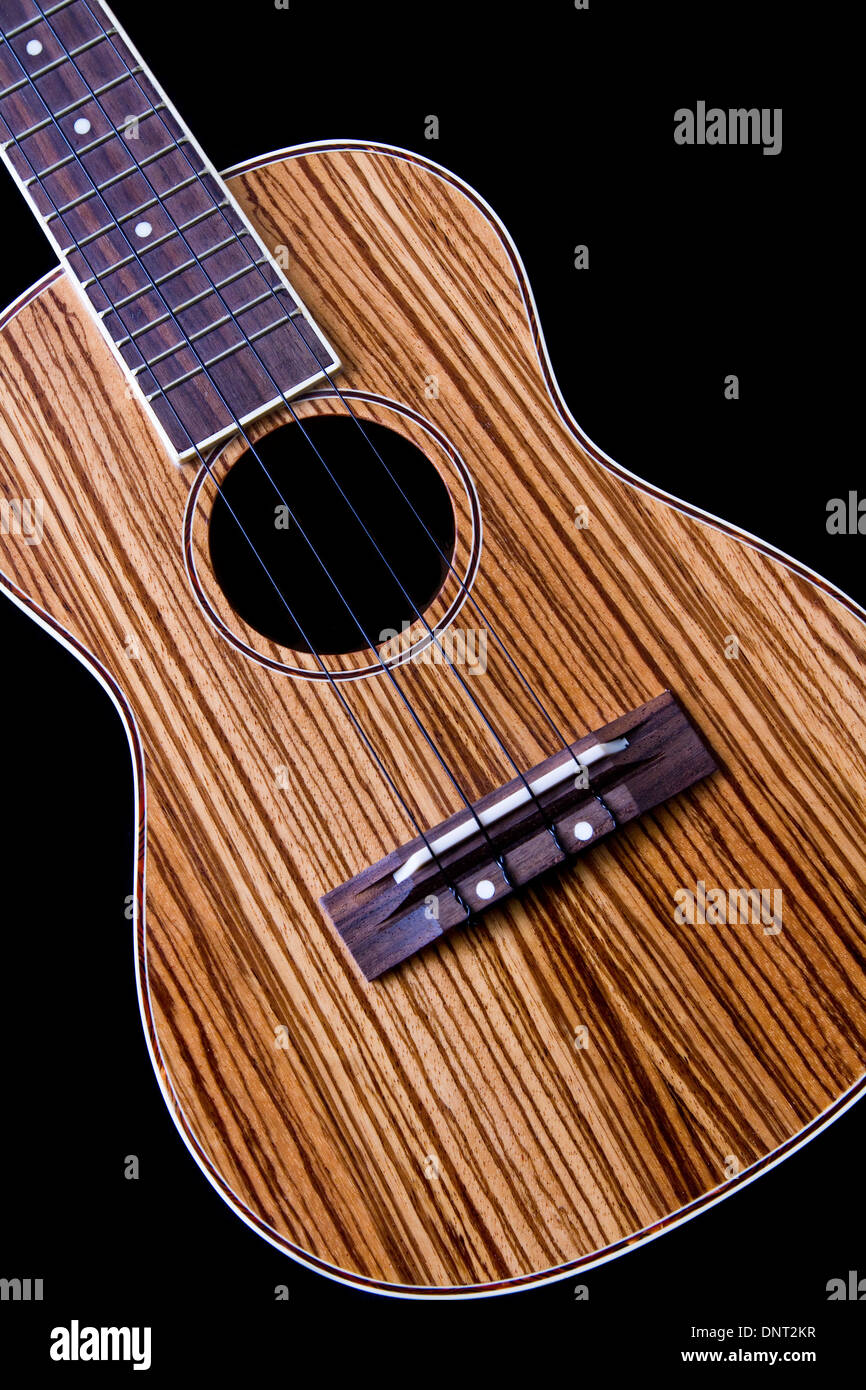 A ukulele acoustic guitar with a beautiful zebra wood top isolated on black background. Stock Photo