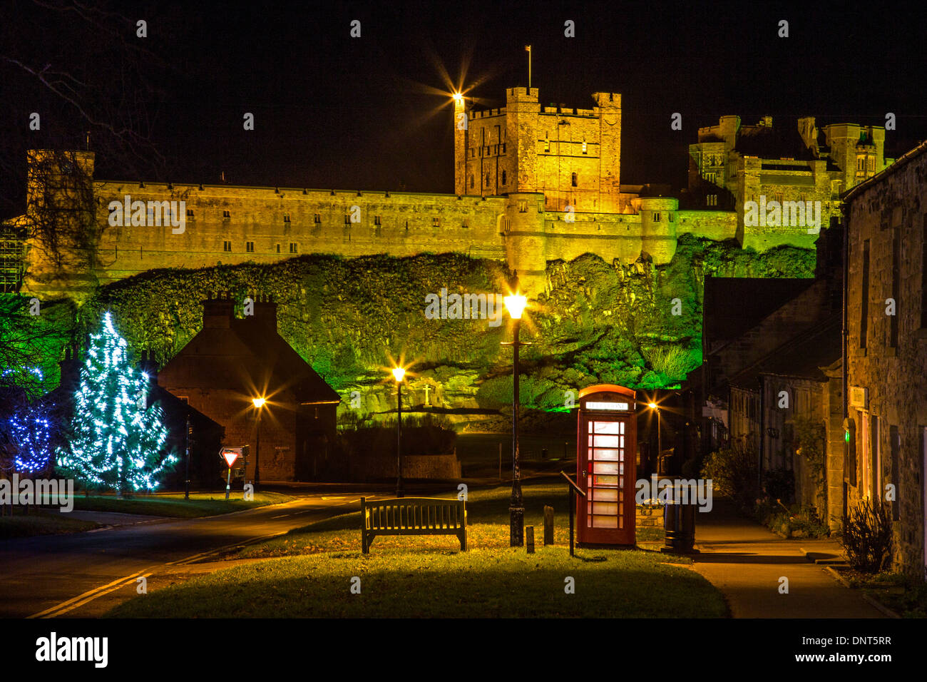 A night-time view of Bamburgh Castle in Northumberland floodlit at Christmas looking from Bamburgh Village Stock Photo