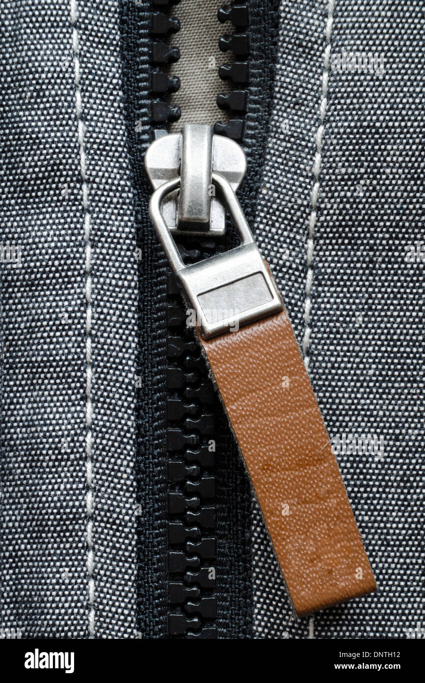 fragment of open plastic zipper fastener with brown leather tag Stock Photo