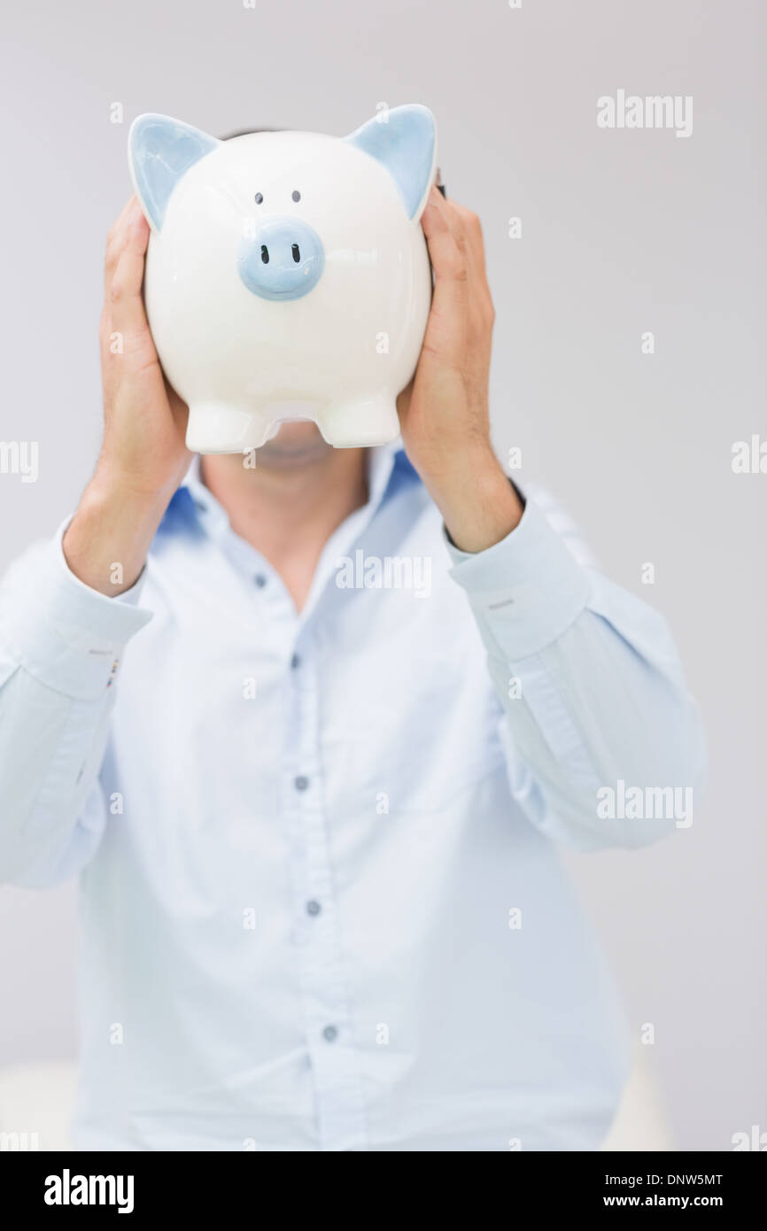 Casual man holding piggy bank in front of his face Stock Photo - Alamy