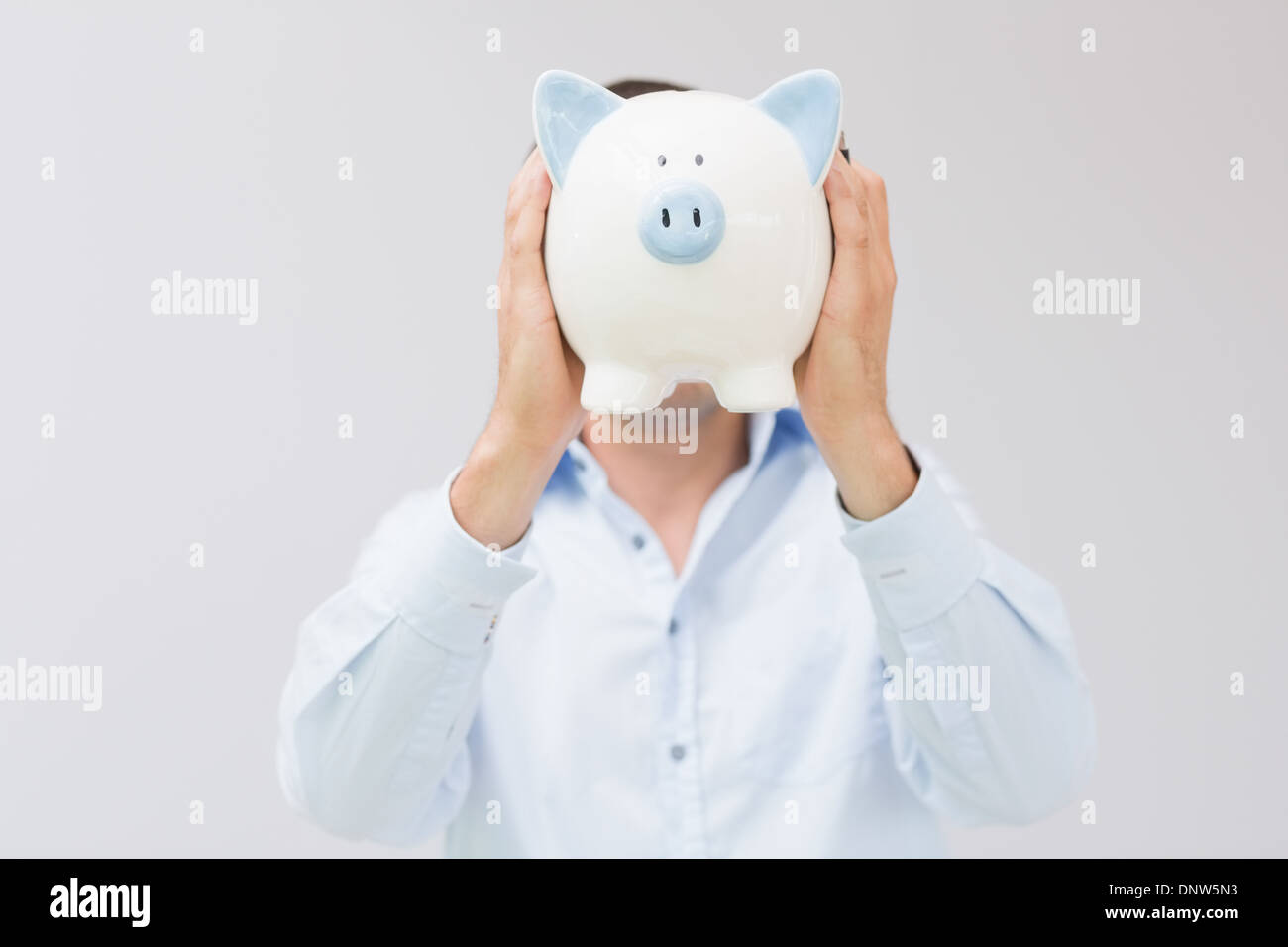 Casual man holding piggy bank in front of his face Stock Photo - Alamy