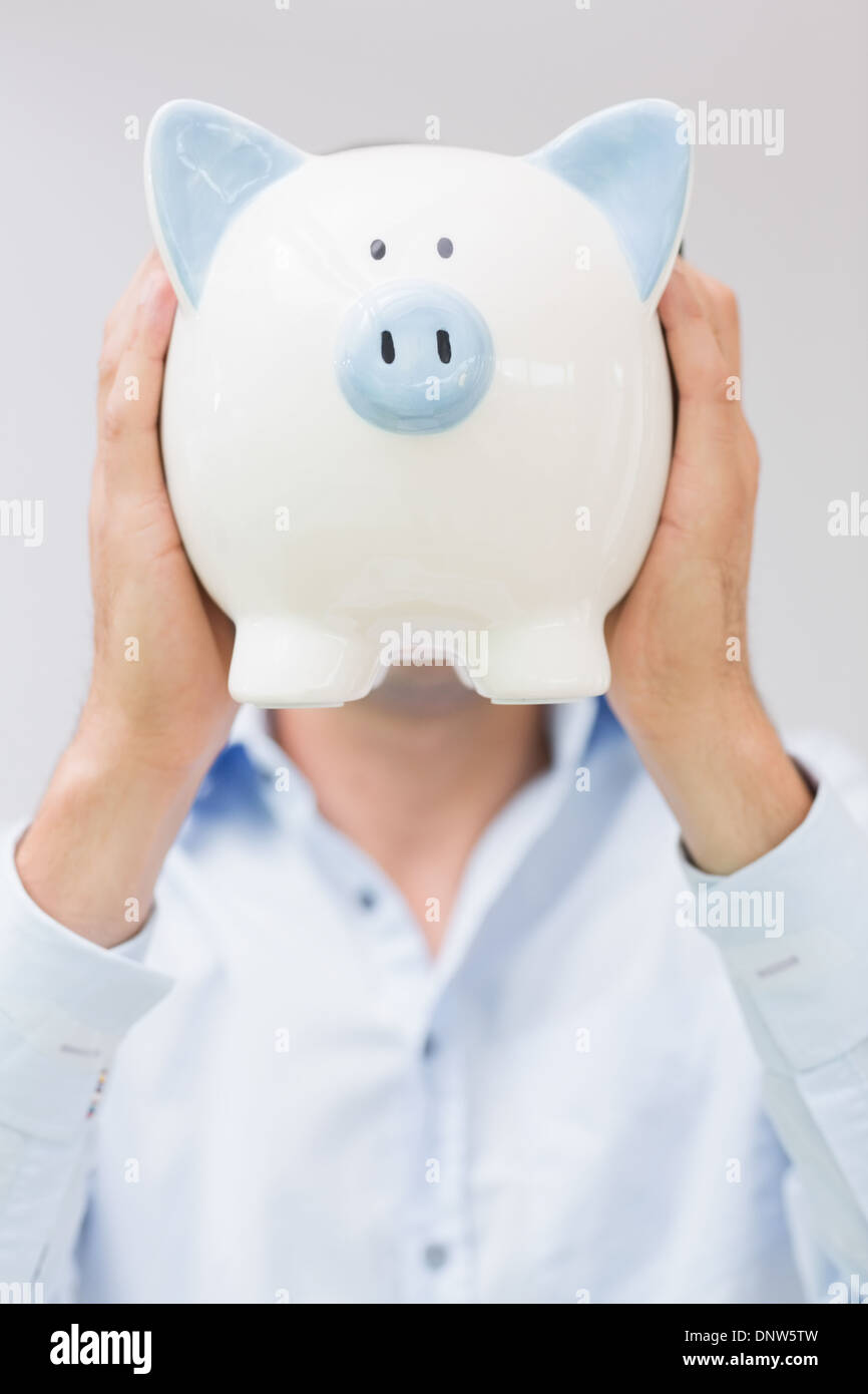 Casual man holding piggy bank in front of his face Stock Photo - Alamy