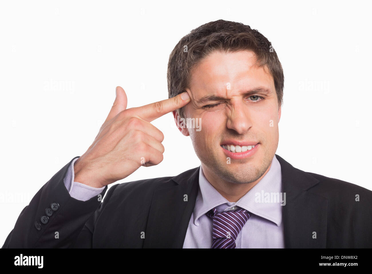 Businessman holding fingers against temple in gun gesture Stock Photo