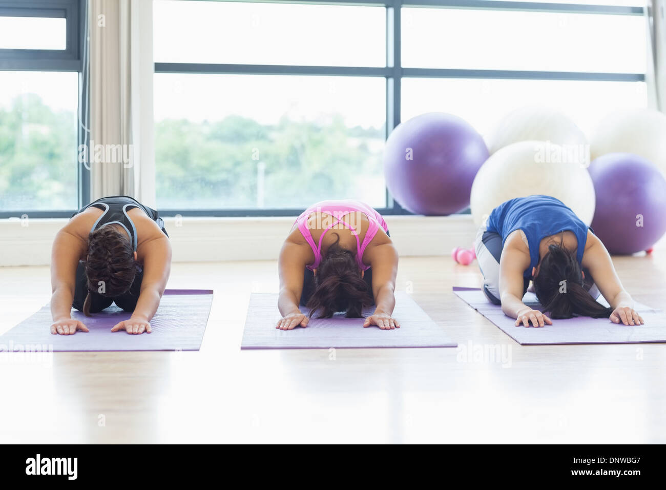 Fit women bending over on exercise mats in fitness studio Stock Photo