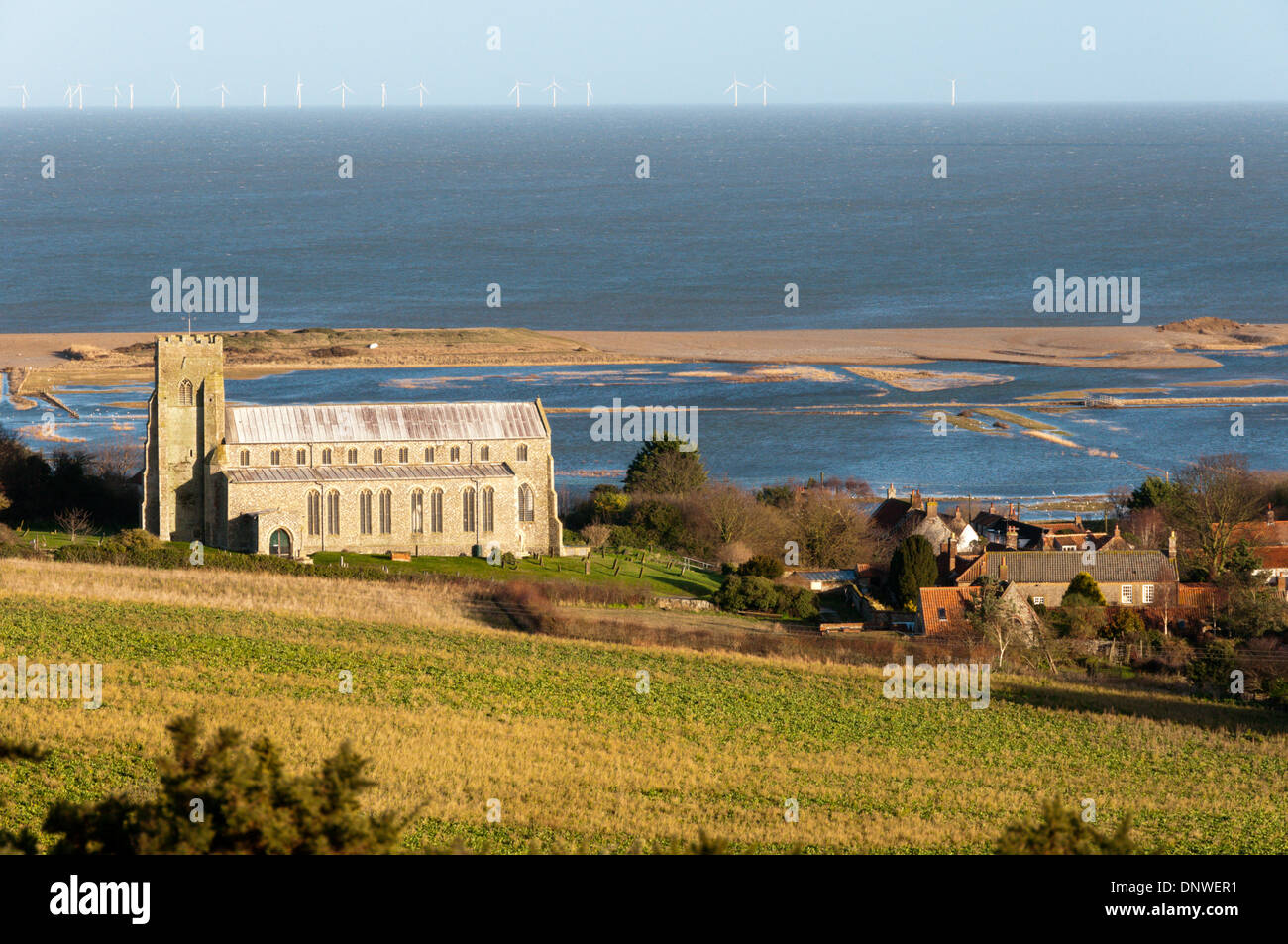 Salthouse St Nicholas church in front of flooded saltmarshes with Sheringham Shoal windfarm on horizon. Stock Photo