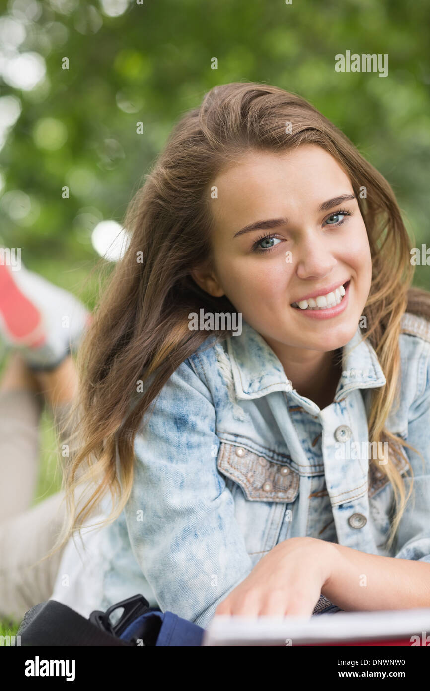 Smiling young student lying on grass Stock Photo