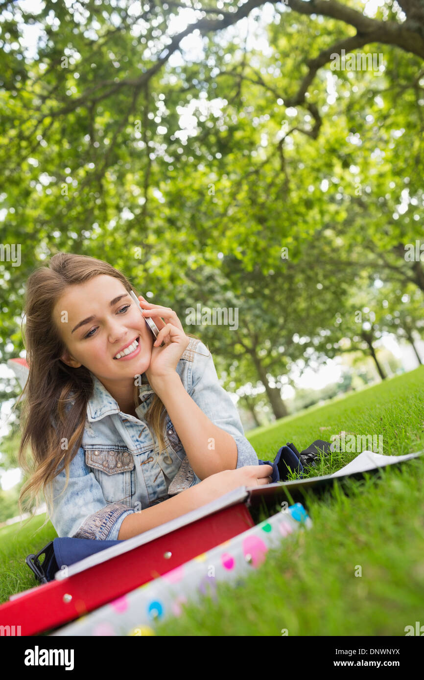 Young happy student lying on the grass on the phone Stock Photo