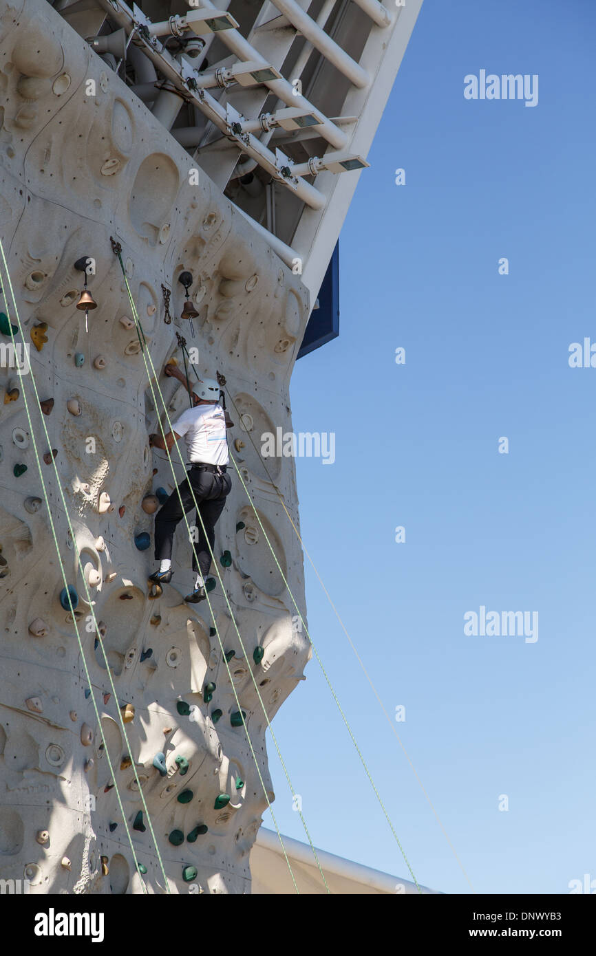 An older man climbing on a rock wall with safety harness and helmet Stock Photo