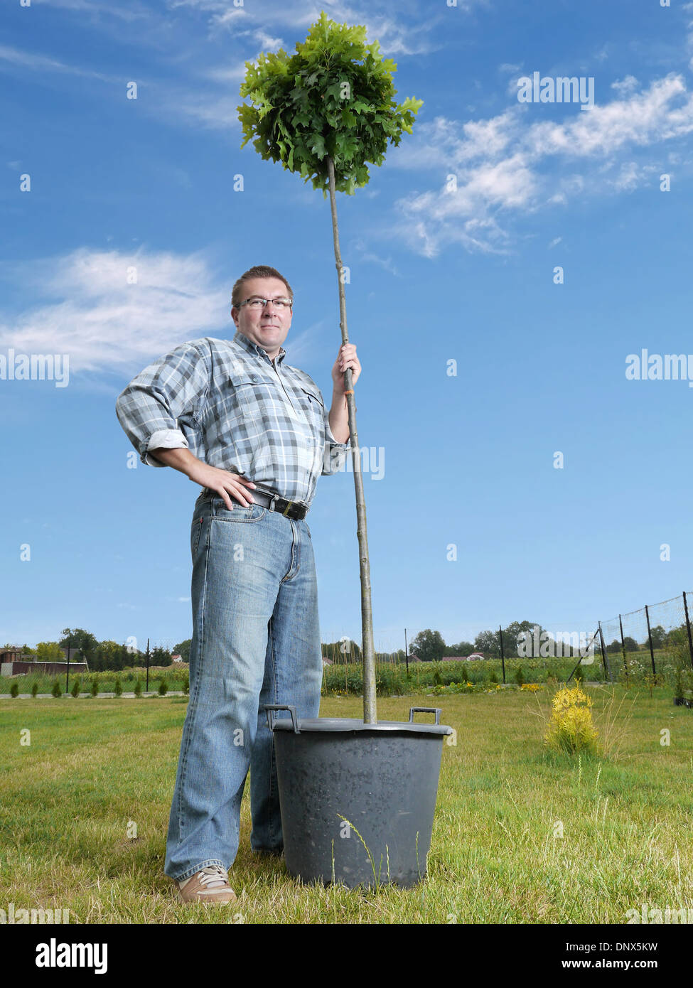 Young man posing with potted oak tree ready for planting in the ground Stock Photo
