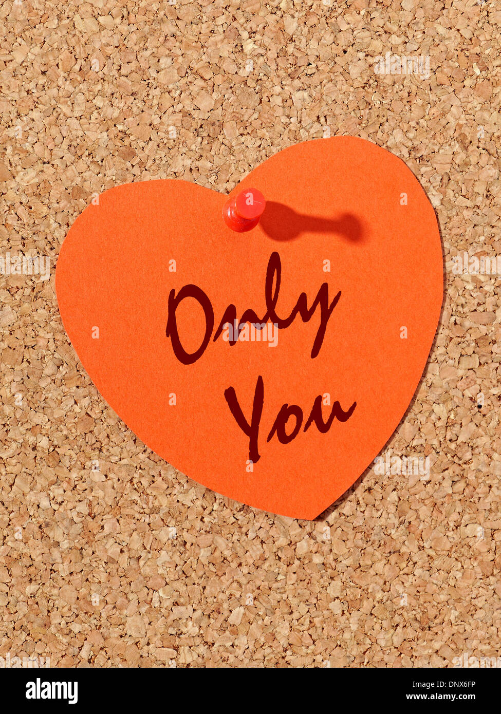 Red paper heart with Only You text pinned to the corkboard Stock Photo