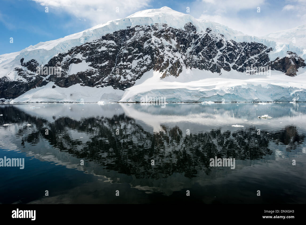 Neko Harbour Landscape Reflection Antarctic Peninsula // NEKO HARBOUR, Antarctica—The icy and rocky scenic landscape mountains covered in ice and snow at Neko Harbour on the Antarctic Peninsula is reflected on glassy mirror-like calm waters. Stock Photo