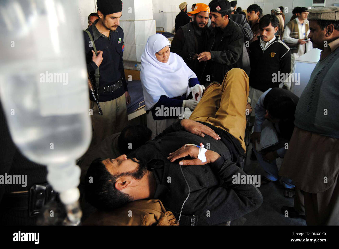 Injured police official is being admitted at local hospital for treatment after unknown armed persons opened fire on two policemen performing their duties outside a private bank in the suburban Mattani area in Peshawar on Monday, January 06, 2014. Stock Photo
