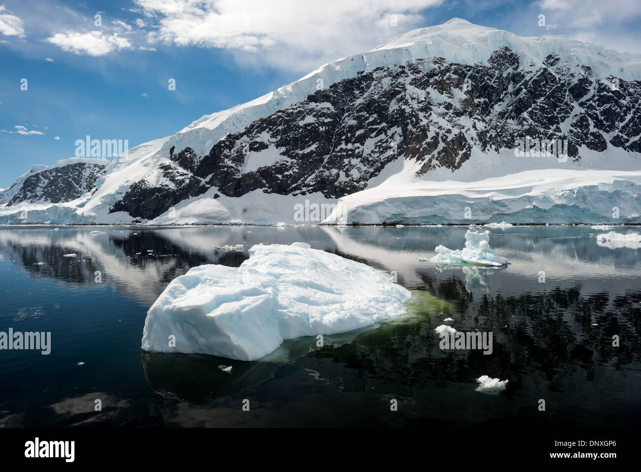 Neko Harbour Scenic Landscape Antarctic Peninsula // NEKO HARBOUR, Antarctica—The icy and rocky scenic landscape mountains covered in ice and snow at Neko Harbour on the Antarctic Peninsula is reflected on glassy mirror-like calm waters. Stock Photo