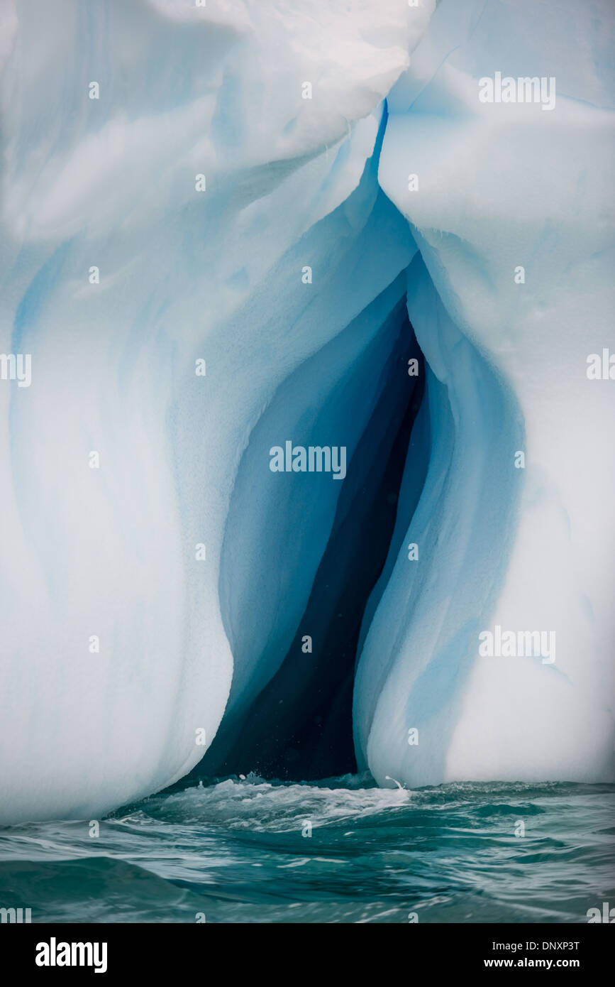 ANTARCTICA - An inverted crevice carved into an iceberg floating on the waters of Curtis Bay, Antarctica Stock Photo