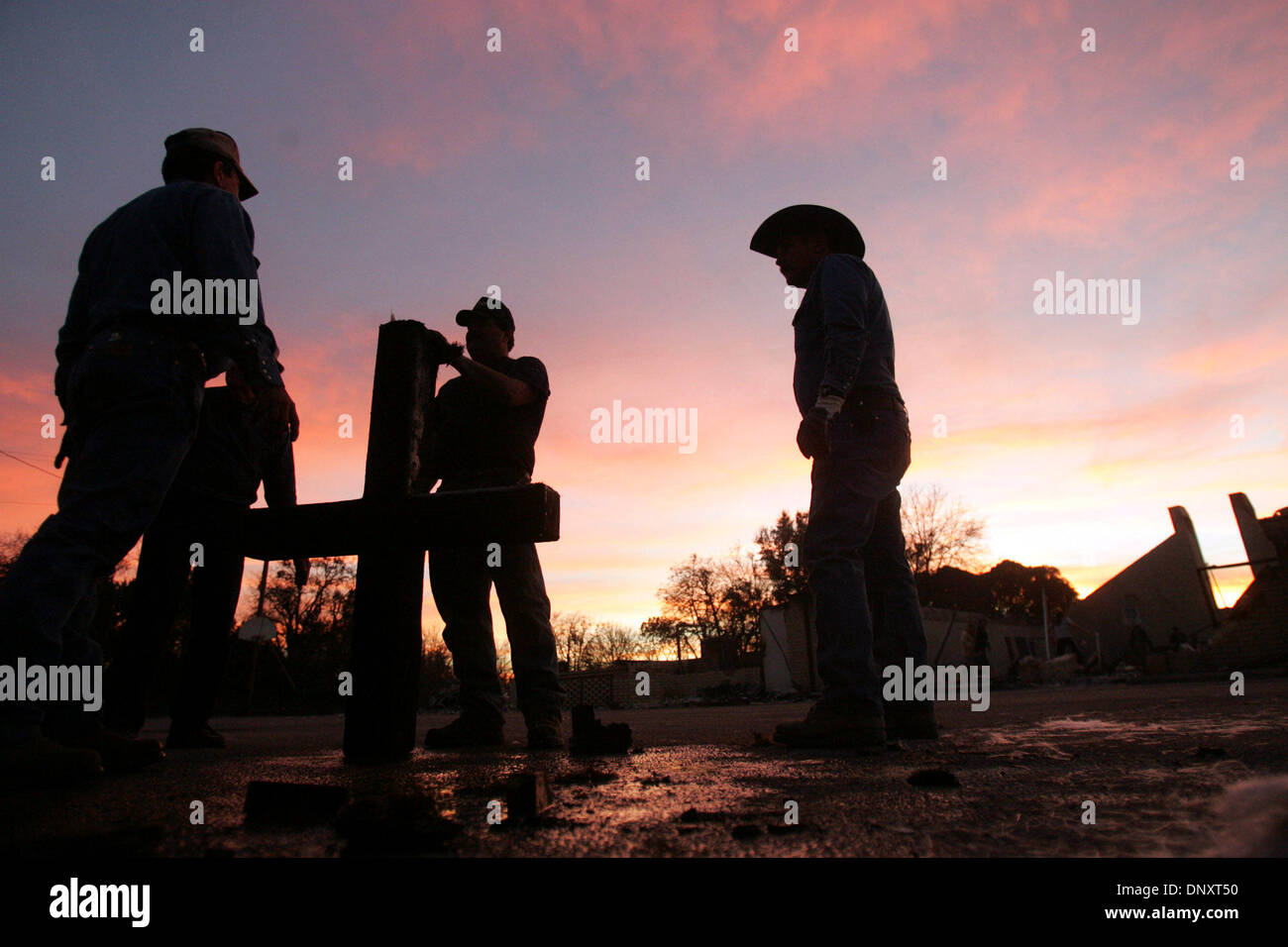 Dec 28, 2005; Cross Plains, TX, USA; Curtis Cooper, from left, Tony Wyatt, and Tim Byrley hold the cross that once stood atop First United Methodist Church of Cross Plains after a devastating grass fire in Cross Plains, TX on Wednesday, December 28, 2005. The men cut off part of the most burnt part of the cross with a saw. Mandatory Credit: Photo by L. Krantz/San Antonio Express-N Stock Photo