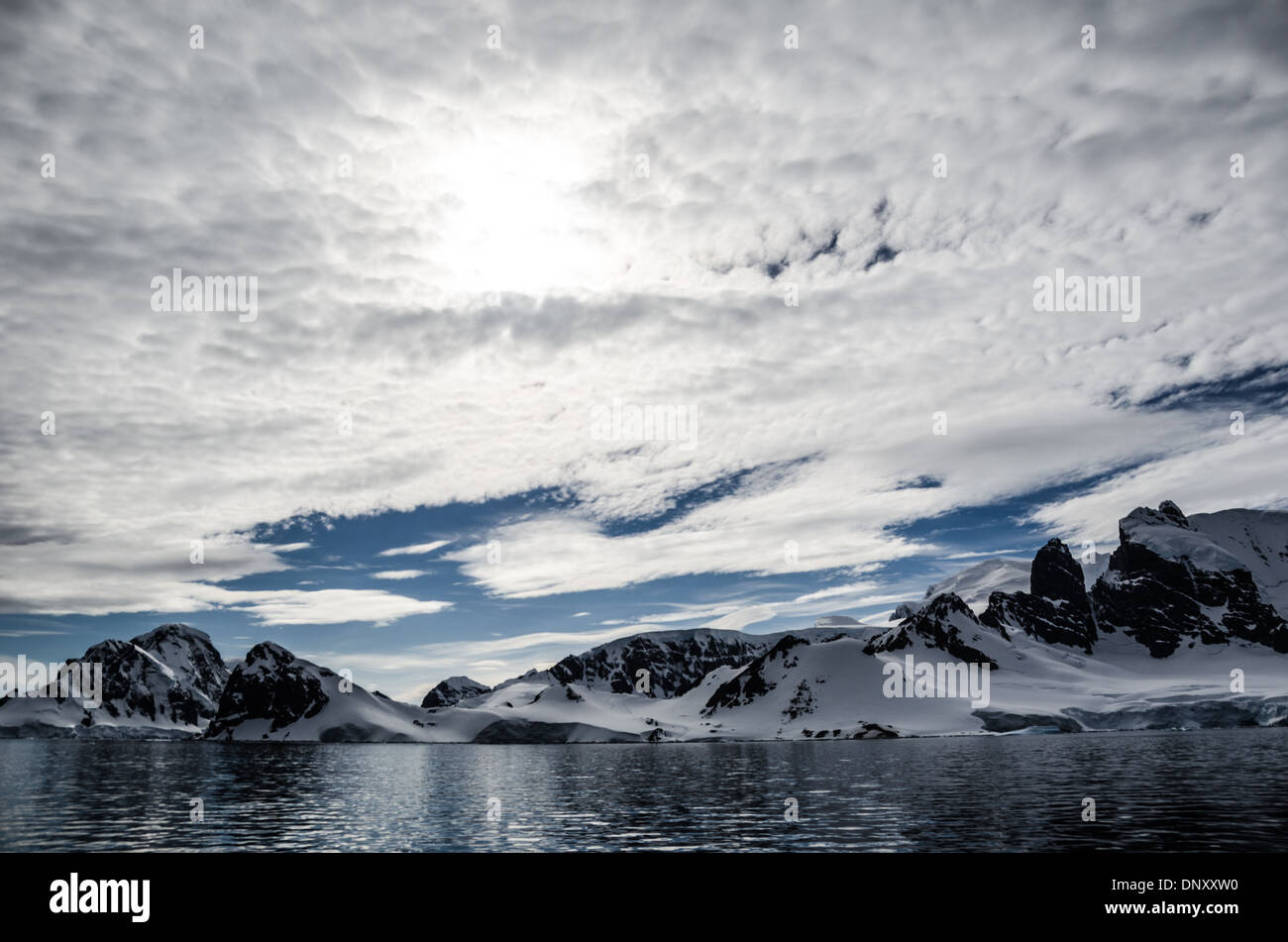 Cuverville Island Antarctic Peninsula Clouds And Sun // ANTARCTICA - A light layer of high clouds partially obscures the sun above Cuverville Island on the western side of the Antarctic Peninsula. Stock Photo