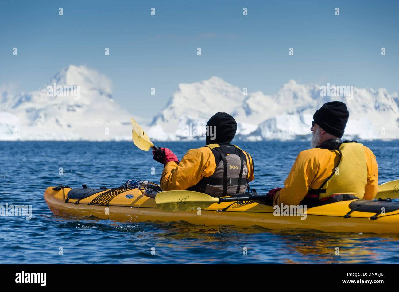 CUVERVILLE ISLAND, Antarctica — Kayakers pause to admire the breathtaking scenery on a clear, sunny day at Cuverville Island on the Antarctic Peninsula. The pristine landscape of snow-capped mountains, glaciers, and calm waters provides a stunning backdrop for these adventurers as they explore one of the most remote and beautiful places on Earth. Stock Photo