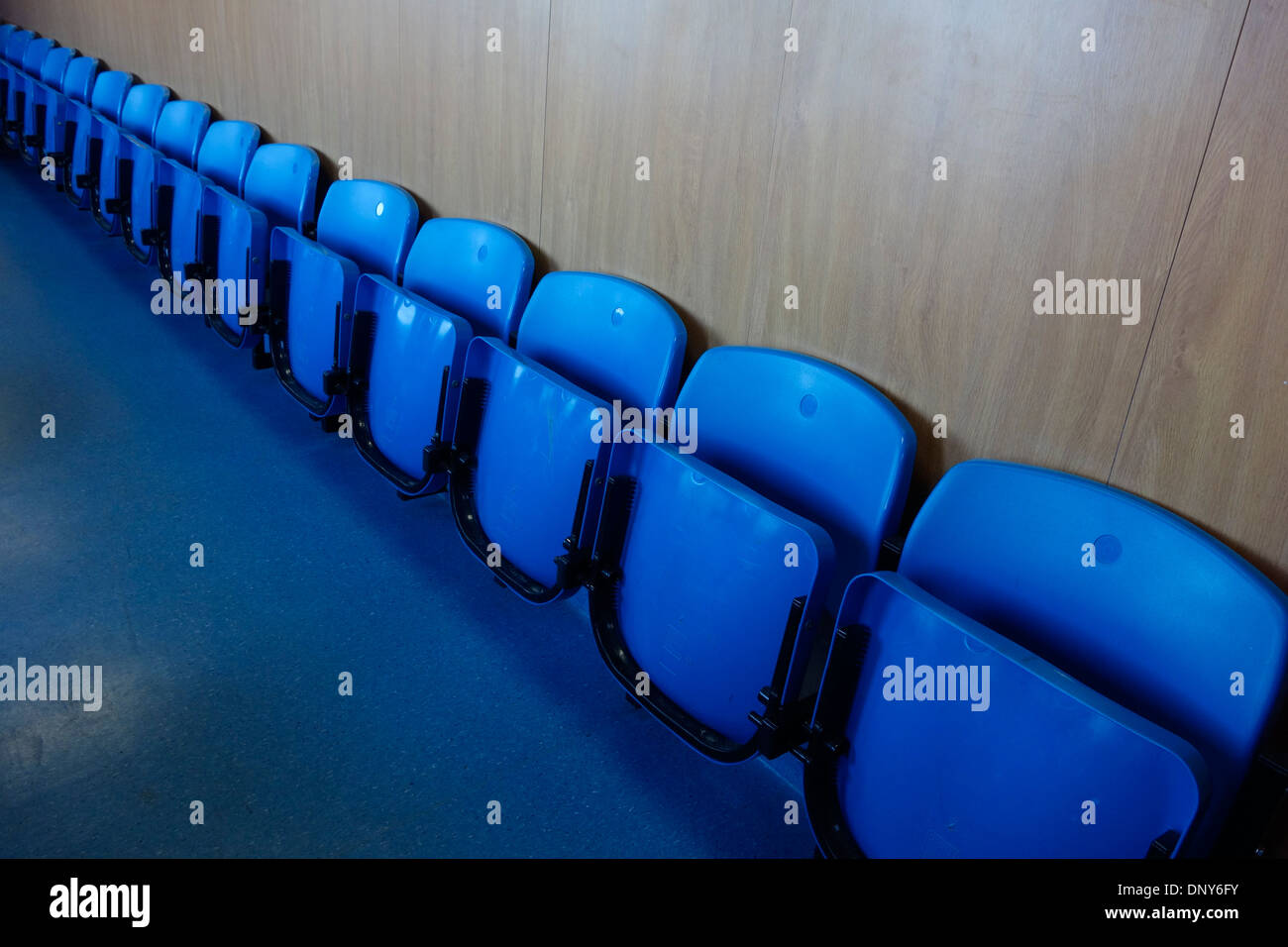 Blue folded and empty plastic seats stretched in a diagonal row. Stock Photo