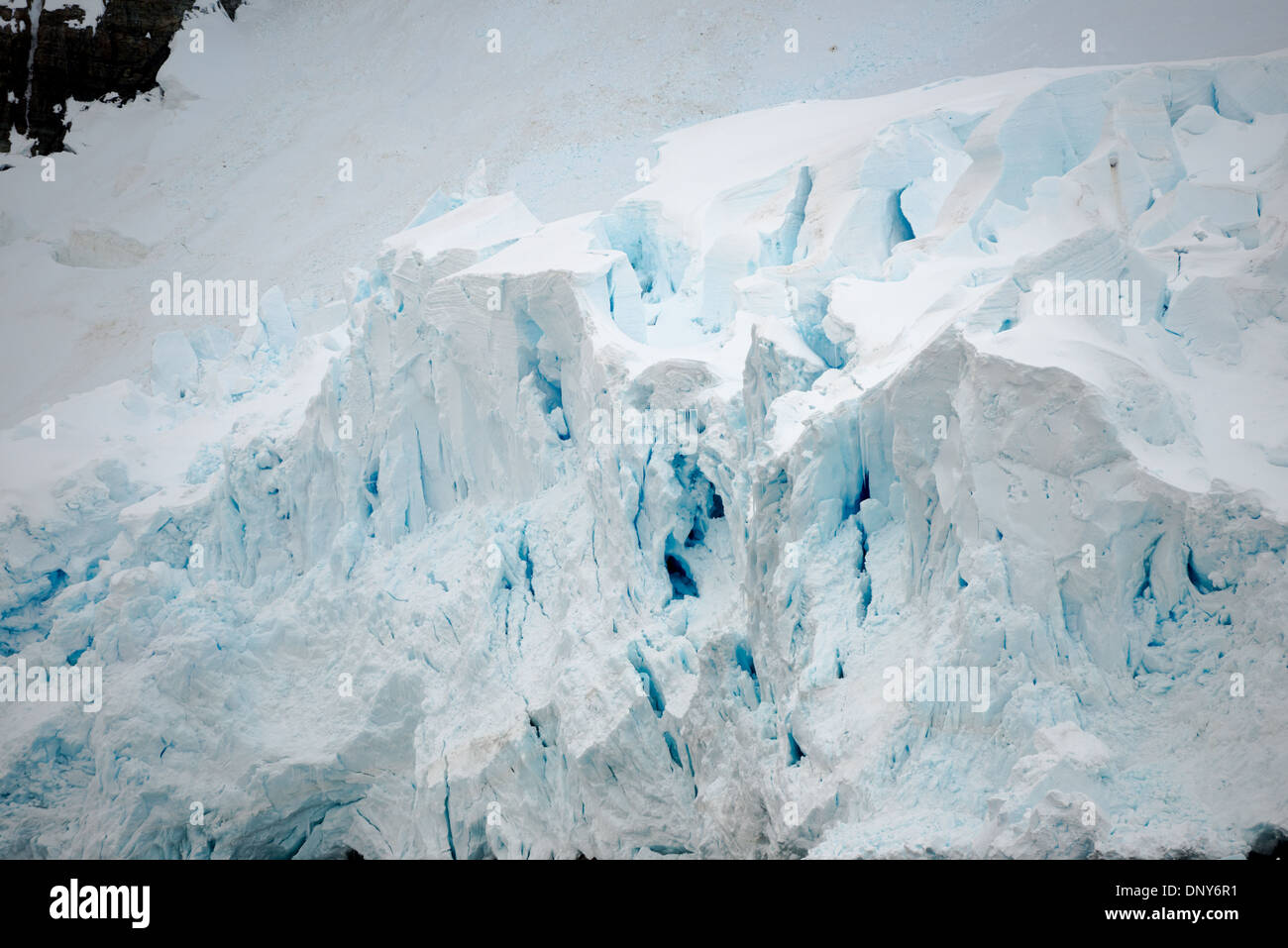 ANTARCTICA - A glacier of thick ice and snow gradually falls into the sea as it flows down the side of the mountains at the Lemaire Channel in Antarctica. The Lemaire Channel is sometimes referred to as 'Kodak Gap' in a nod to its famously scenic views. Stock Photo