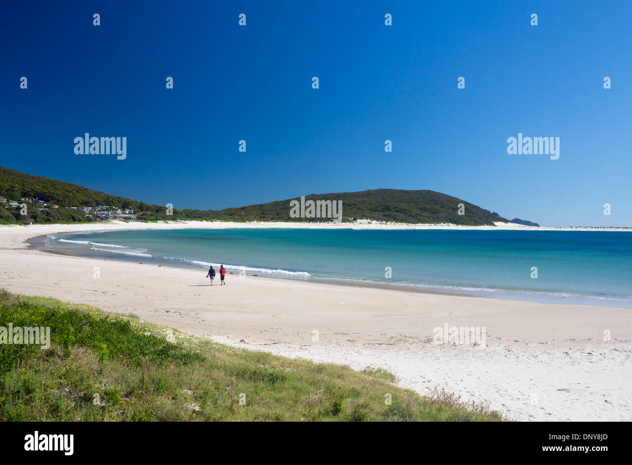 Fingal Beach bay with two women people walking along shoreline Port