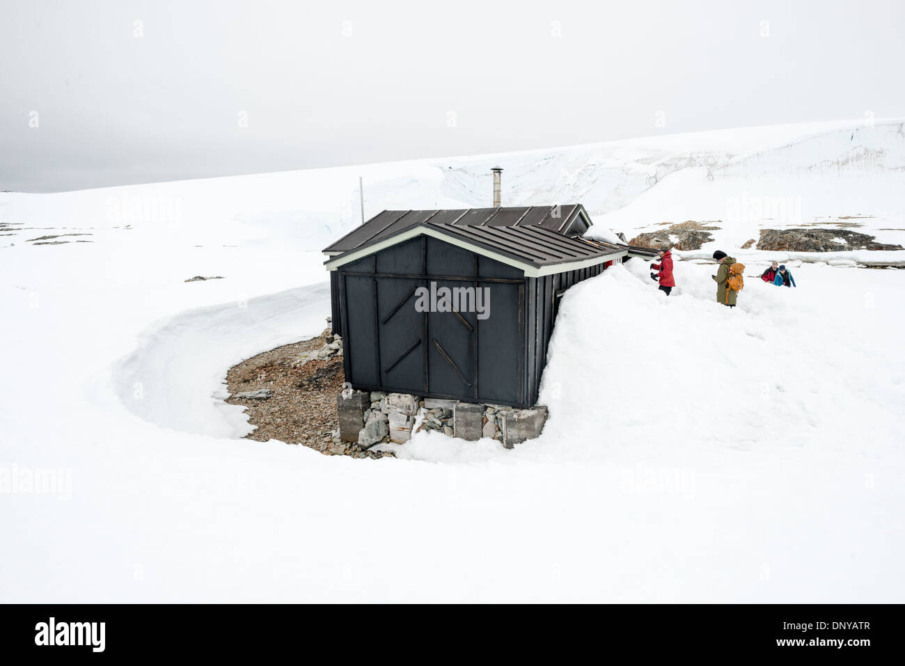 Wordie House Historic Site Winter Island Antarctica // WINTER ISLAND, Antarctica — Tourists explore the historic site of Wordie House, originally known as Base F. Originally established in 1947 as Base F by the Falkland Islands Dependencies Survey, the successor organization to Operation Tabarin, and later renamed after James Wordie, chief scientist and geologist on Ernest Shackleton's Endurance expedition, this research station is preserved near Vernadsky Research Base in the Argentine Islands. Stock Photo
