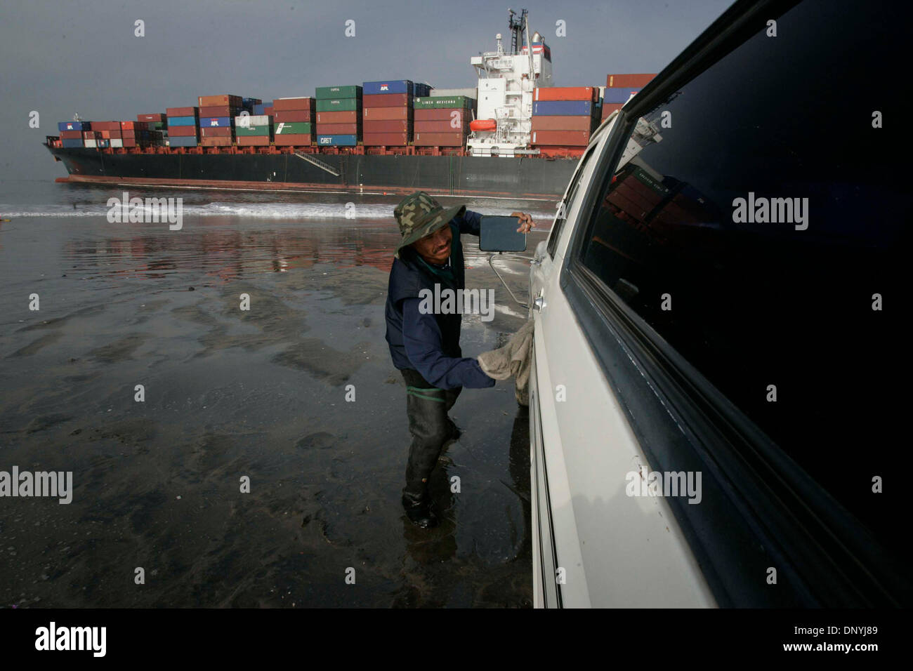 Jan 30, 2006; Ensenada, BC., Baja California, MEXICO; Diver/boat handler JUAN JIMENEZ took time between between his chores at the stranded container ship APL Panama to wipe the sand and salt of of his truck on the beach adjacent to the ship on Monday. Salvors are hopeful series of high tides over the next three days, along with more tugging power and a powerful water jet to blow sa Stock Photo