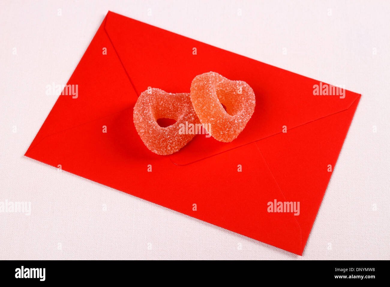 Two hearts from sugar candies on red love letter, close up Stock Photo