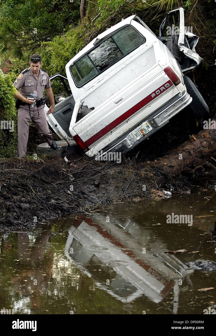 Feb 22, 2006; Palm City, FL, USA; Florida Highway Patrol Trooper Gottfried Koblitz steps through the mud to photograph the scene of this truck crash. The Ford pickup went off the road in front of 4406 Loop Road in Palm City and crashed through a canal and into the woods. Two victims were flown to St. Mary's in West Palm Beach and a third was taken by ambulance to Martin Memorial Me Stock Photo