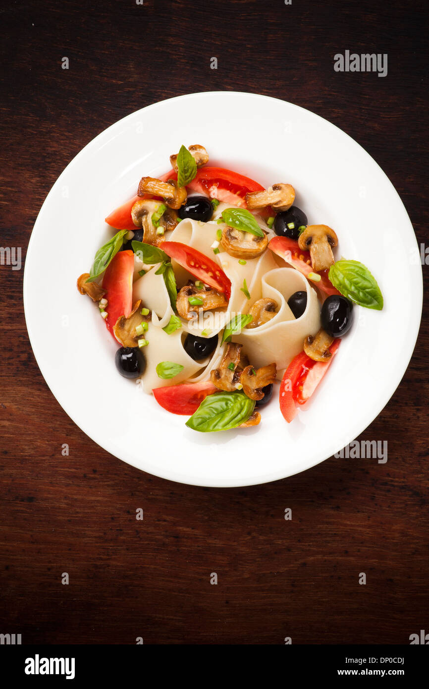 Pasta pappardelle with mushrooms, tomatoes, olives and basil leaves Stock Photo