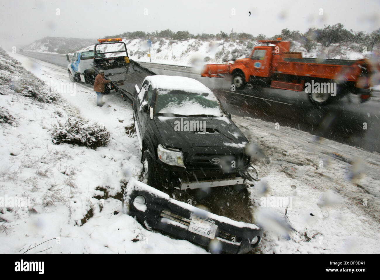 Mar 10, 2006; San Diego, CA, USA; Richard Steele with Jacumba Towing hooks up a wrecked pickup to load on his rollback on the south side of I-8 a couple miles west of the Ribbonwood Rd. exit. (TB: 1298 D-5) as a snow plough drives by. Mandatory Credit: Photo by John R. McCutchen/SDU-T/ZUMA Press. (©) Copyright 2006 by SDU-T Stock Photo