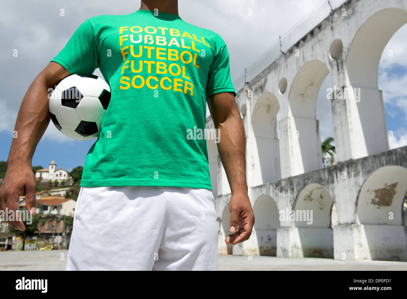Brazilian soccer player wearing international football shirt holding soccer ball at Lapa Arches in Rio de Janeiro Stock Photo