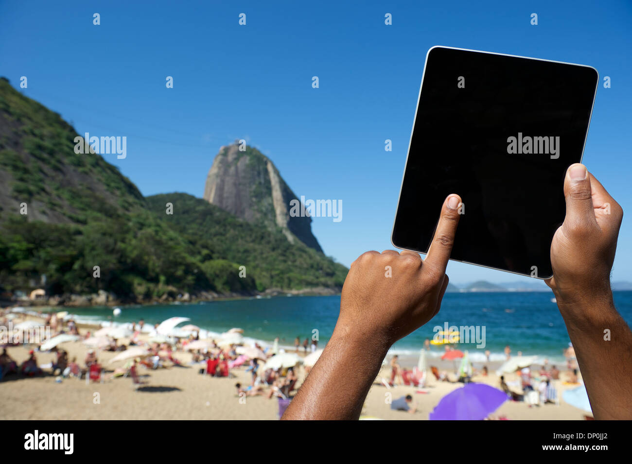 Brazilian hands using tablet computer at Praia Vermelha Red Beach ...