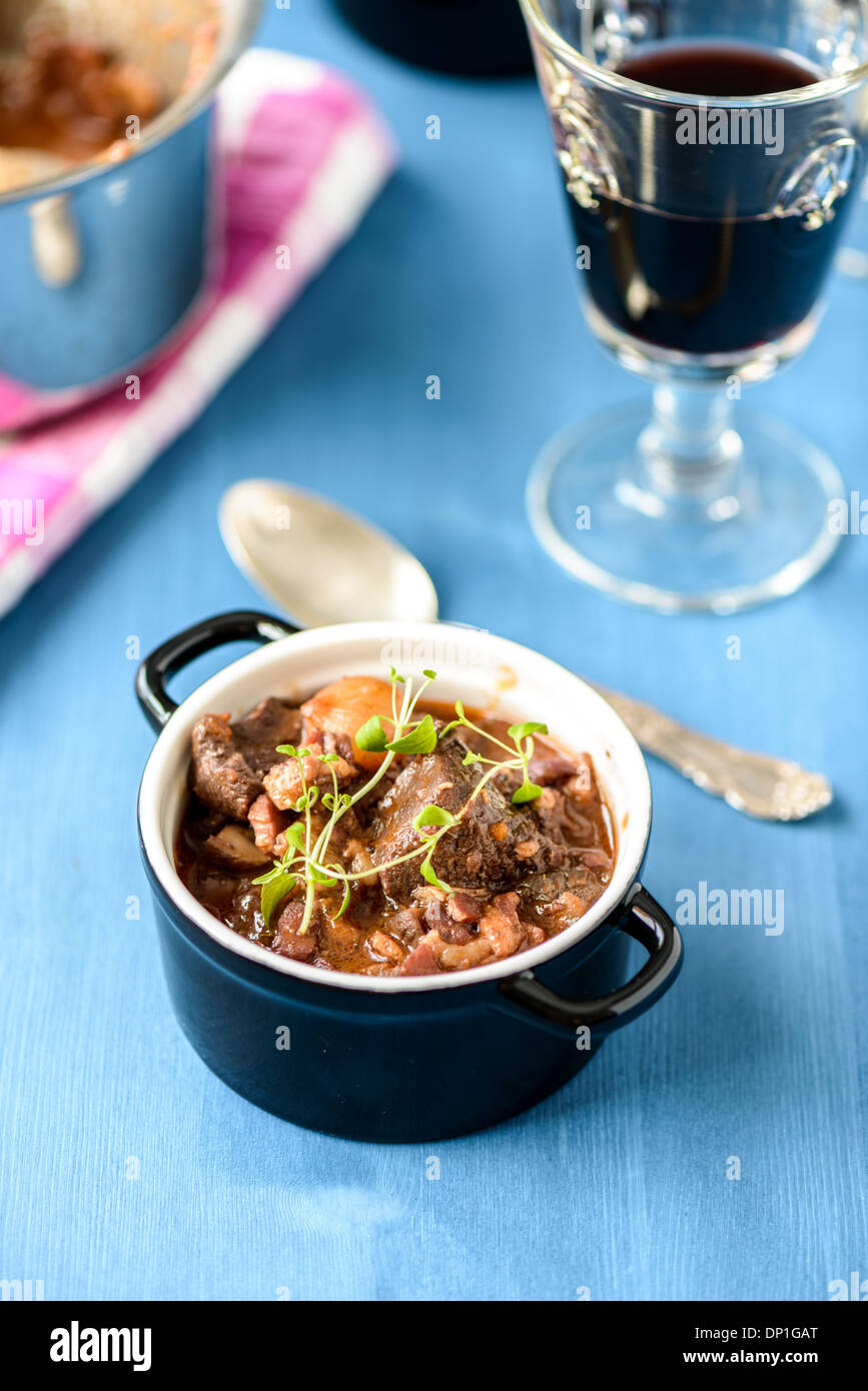 boeuf bourguignon classic french beef stew on blue table with a glass of red wine Stock Photo