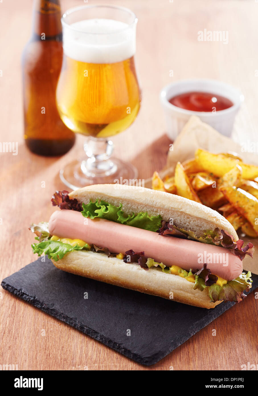 Gourmet hot dog on slate board with rustic fries Stock Photo
