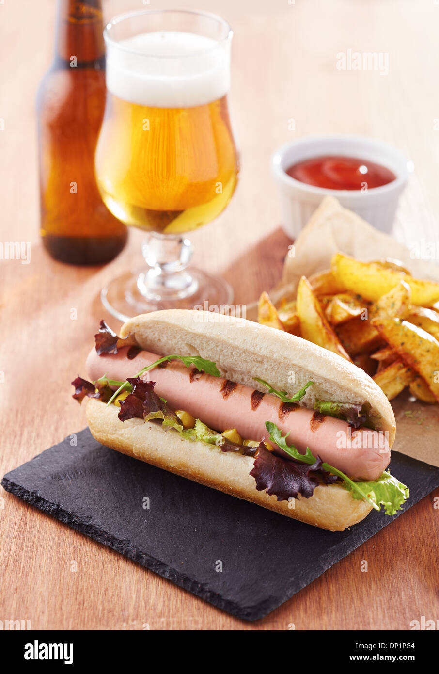 Gourmet hot dog on slate board with rustic fries Stock Photo