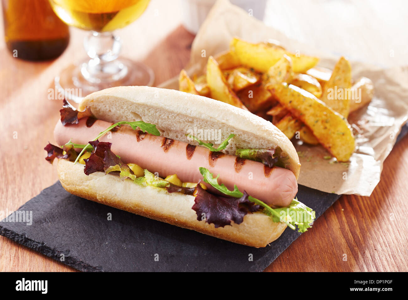 Gourmet hot dog on slate board with rustic fries Stock Photo