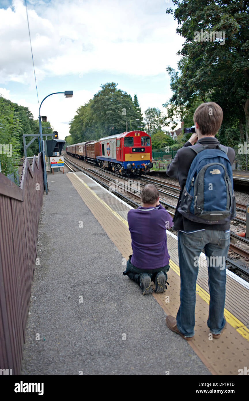 Two railway enthusiasts photograph a class 20 diesel approaching Chorleywood station during the Met150 celebrations Stock Photo