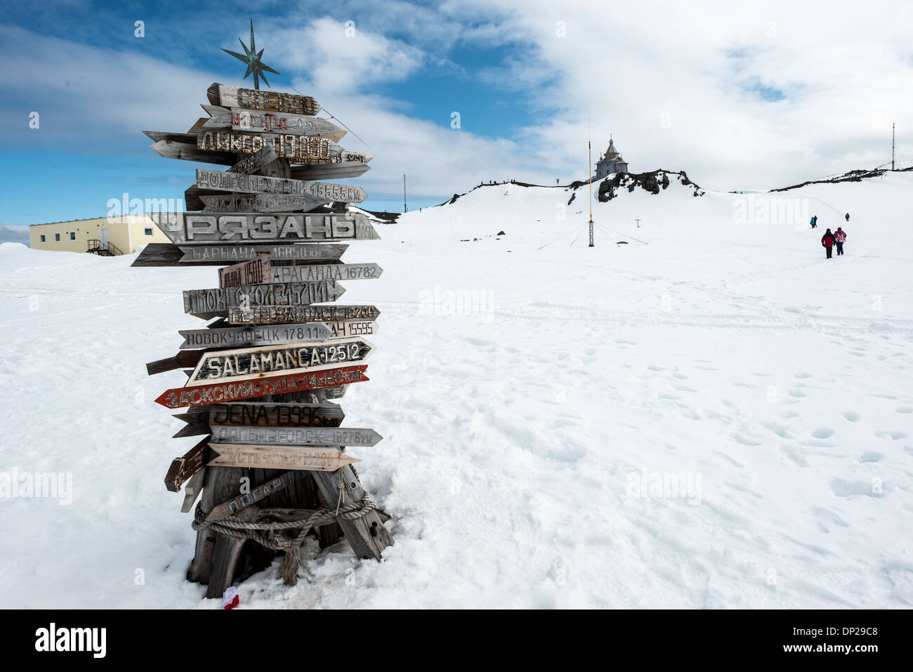 ANTARCTICA - Signposts in Russian point to world destinations and their distance from Bellingshausen Station research base on King George Island in the South Shetland Islands. In the background at right is Trinity Church. Stock Photo