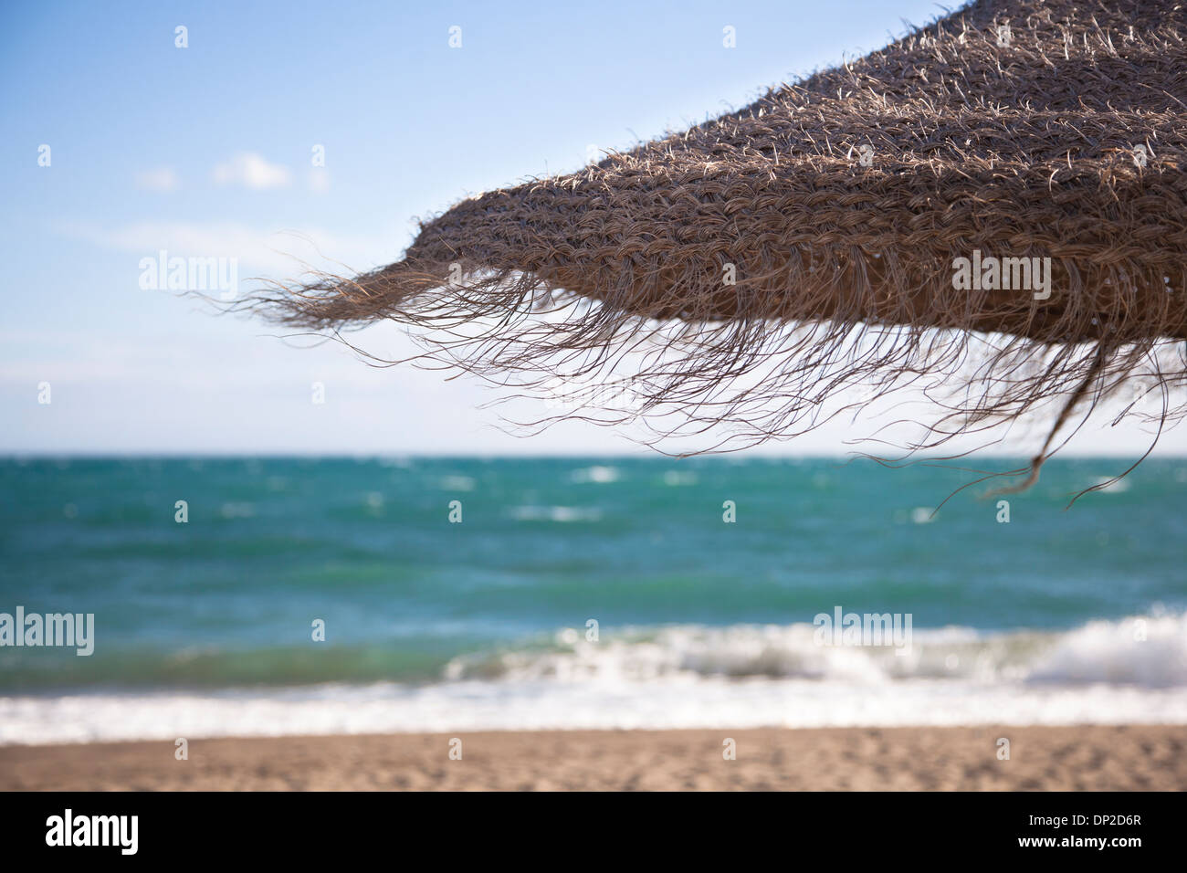 Close up of straw parasol in front of the ocean. Stock Photo