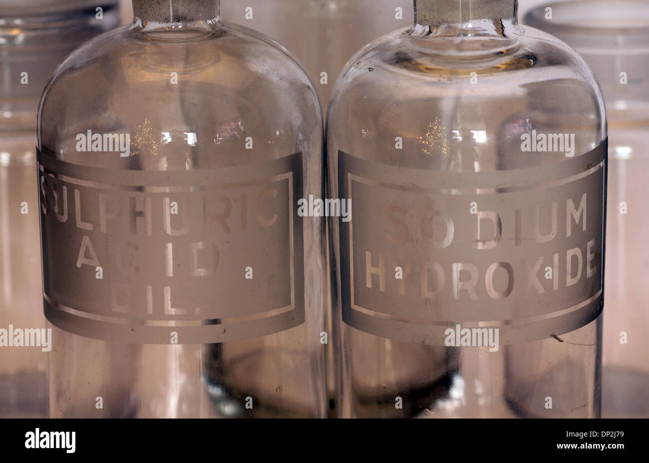 macro view of old glass chemistry bottles labeled for sulphuric acid diluted and sodium hydroxide Stock Photo