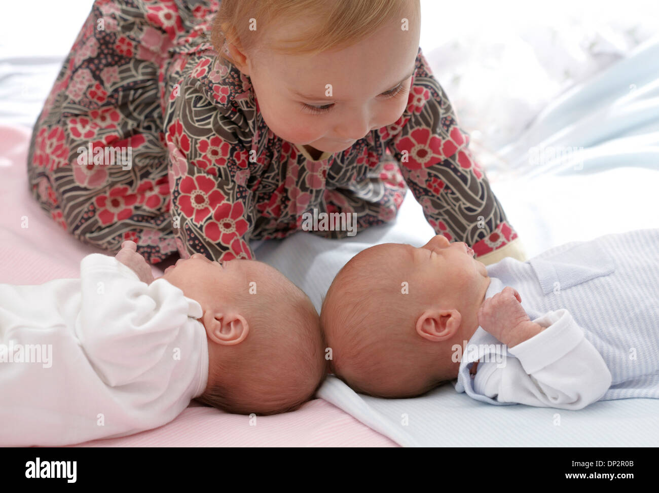 One year old girl with baby twin siblings Stock Photo